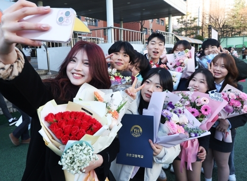 졸업식서 꽃다발을 들고 사진을 찍는 학생들의 모습