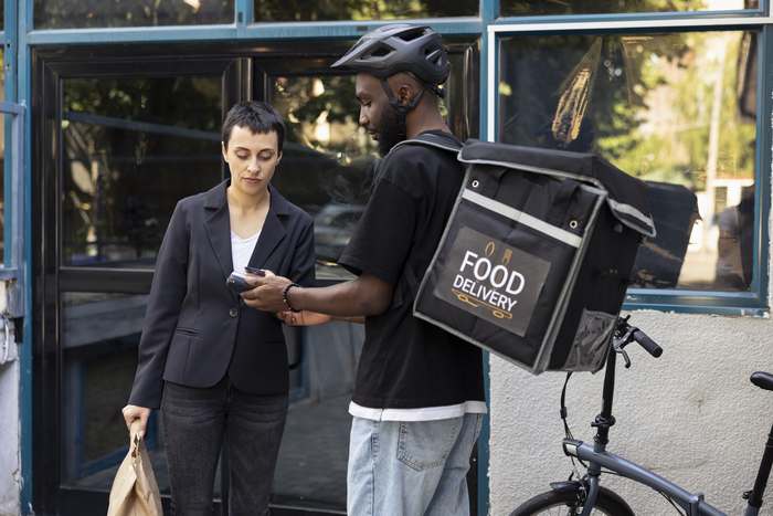 Black delivery worker accepts electronic payment from customer