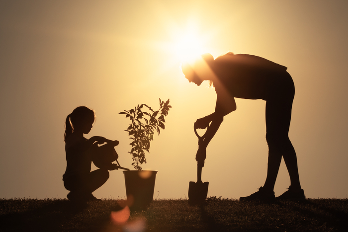 Mother and daughter planting a family tree in the garden.